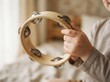 © SimpleDesignStudio - Toddler playing wooden tambourine, close up view of child hands with percussion musical instrument for early learning