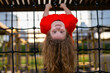 © Volodymyr - Upside down portrait shows playful child. Upside down hanging creates fun concept. Girl smiles upside on playground net. Outdoor play makes upside movement joyful.