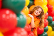 © Volodymyr - Child smiles among colorful birthday balloons. Child peeks through bright festive decoration. Vibrant balloons frame child during celebration. Happy party colors surround child closely.