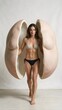 © kazetix - Conceptual full-body portrait of a confident woman in a black bikini walking forward, framed by large cracked clay muscular sculptures, symbolizing body contouring, physical transformation, and aesthe