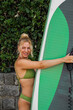 © phoenix021 - Closeup shot of pretty blonde woman posing with stand up paddleboard , smiling and looking away