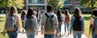 © Maryna - Students walk to school with backpacks on a sunny day. Diverse teens approach building entrance ready for learning, friendship, and new academic year.