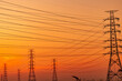 © Fahroni - High voltage electricity transmission towers and power lines silhouetted against sunset sky. Electrical grid infrastructure, energy distribution, utility engineering and modern power networks.