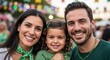 © Angavlan - Smiling Irish family poses together outdoors at a vibrant public parade event, celebrating their heritage. Happy Irish family members wear green attire and accessories,