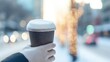 © tashechka - Coffee is held in hand while walking on a city street during the winter season