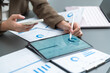 © eggeeggjiew - Businesswoman reviewing financial dashboards on a tablet while checking reports and mobile data for business analysis.