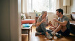 © Rendara Studio - Active senior woman and man laughing with supplement bottle after home yoga session