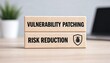 © MD - Wooden blocks displaying vulnerability patching and risk reduction concepts on a light workspace surface