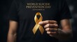 © Mona - A person holding a yellow awareness ribbon for world suicide prevention day on september 10th, symbolizing support and mental health advocacy