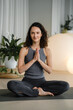 © Alex - Woman practices yoga in a studio with plants and round lights during a morning session focused on mindfulness and relaxation