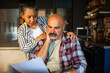 © Marko Geber - Worried couple reviewing bills in home kitchen