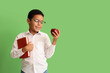 © Pixel-Shot - Little African-American schoolboy with book and apple on green background
