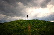 © Cavan Images - Young girl jumping on a hill under stormy clouds