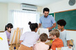 © Kawee - Diverse students coloring on painting board on table at elementary school.
