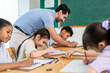 © Kawee - Group of diverse kids coloring paper in classroom at elementary school.