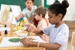 © Kawee - African American girl painting on frame in classroom at elementary school.