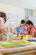 © Kawee - Diverse students coloring on painting board on table at elementary school.
