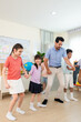 © Kawee - Diverse students dancing with male teacher in classroom at elementary school.