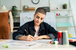 © Kawee - Caucasian young woman working as fashion designer in tailor studio.