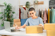 © Kawee - Caucasian woman checking customer orders on laptop in clothing store.