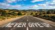 © Md Arif Babu - Never Give Up motivational message painted on asphalt road, winding highway through sunny mountain landscape, concept of perseverance and success