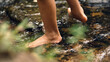 © DEWINs - Close-up of a barefoot child walking through a shallow forest stream over smooth rocks, enjoying grounding, sensory play, outdoor exploration, and a natural connection with the environment.
