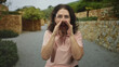 © Krakenimages.com - Woman cups hands to mouth shouting on a stone street beside a low rock wall and shrubs; urgent call.