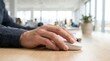 © Lamduan - In an office setting, a closeup shows a man's hand using a computer mouse on a wooden desk.