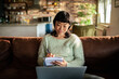 © Davor - Woman writing notes while working from home on sofa