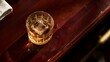 © Kitta Studio - Glass of whiskey with ice cube on wooden bar counter in warm lighting