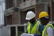 © ultramansk - African construction workers planning green energy installation carry the solar module along the row of unfinished houses outdoors at a modern housing estate project, candid real moment