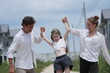 © ultramansk - Cheerful Caucasian family of three swing their laughing daughter by the arms as they walk among modern new houses of a suburban housing estate. Concept of family love, care and quality time