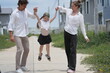 © ultramansk - Happy young family with little daughter celebrate as the girl jumps and dad scoops her up on a walk through a new suburban housing development on a bright sunny day