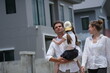 © ultramansk - Young parents and their playful child celebrate as the girl jumps and dad scoops her up outdoors on the street of a newly built residential neighborhood, shallow depth of field