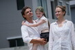 © ultramansk - Cheerful Caucasian family of three cheer while their daughter leaps ahead on the road among modern new houses of a suburban housing estate on a bright sunny day