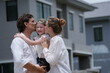 © ultramansk - Young parents and their playful child hold their child close pointing out their future house outdoors on the street of a newly built residential neighborhood in warm natural light