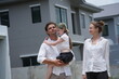 © ultramansk - Young parents and their playful child play catch and carry with their excited child outdoors on the street of a newly built residential neighborhood, candid real moment