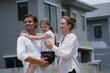 © ultramansk - Cheerful Caucasian family of three embrace the girl and admire the freshly built homes outdoors on the street of a newly built residential neighborhood, candid real moment