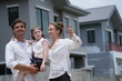 © ultramansk - Young parents and their playful child kiss and hug their daughter while pointing at the new houses among modern new houses of a suburban housing estate, authentic everyday scene