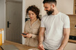 © La Famiglia - Couple sharing morning routine using smartphone in kitchen