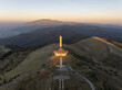 © Amazing Aerial - Aerial view of the Buzludzha Monument on a mountain peak at sunset with surrounding hills and landscape in Stara Zagora, Bulgaria.