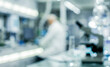 © luxurystudio - A blurred laboratory scene showcasing a scientist in a white lab coat working with scientific equipment and glassware in a modern lab environment.