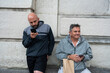 © Nazareno - Two men waiting outdoors using smartphones