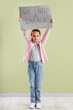 © Pixel-Shot - Protesting little girl holding placard with text WE NEED A CHANGE near green wall. Impeachment concept