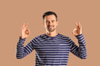 © Pixel-Shot - Handsome man showing OK on brown background