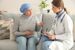 © Pixel-Shot - Mature woman after chemotherapy with doctor at home. Stomach cancer concept