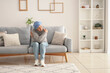 © Pixel-Shot - Mature woman after chemotherapy sitting on sofa at home. Stomach cancer concept
