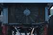 © Ekaterina - Front close up shot of a large black electric cooling fan attached to an engine radiator on an off road race car frame. Mechanical detail showing radiator grill, fan blades, and red suspension springs