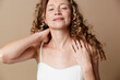 © SHOTPRIME STUDIO - Middle aged woman with curly hair showing natural skin without retouching. Close up portrait on a brown background. Concept of authentic beauty wellness and self care.