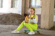 © Anna - Smiling girl sitting on skateboard with chip pack. Concept: Teenage fast food snacks, Urban school autumn break, Youth leisure.